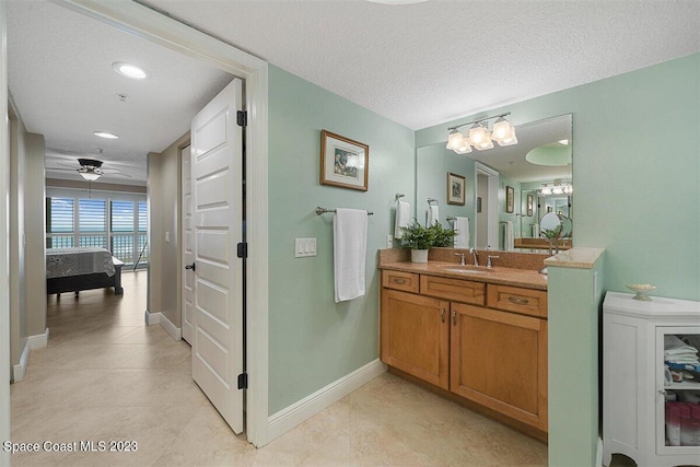 bathroom with ceiling fan, vanity, tile floors, and a textured ceiling