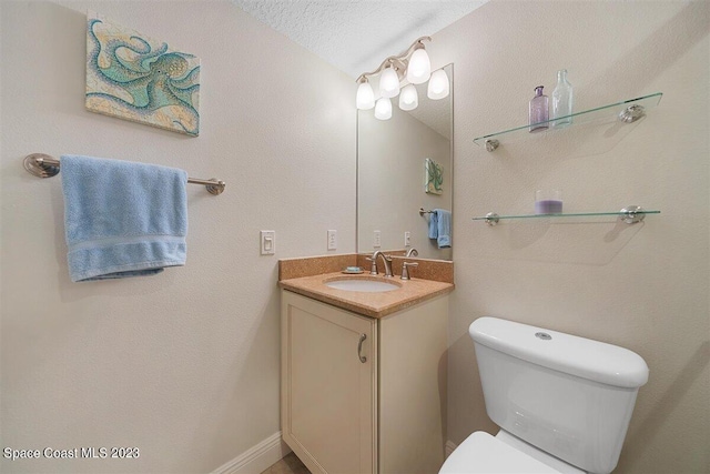 bathroom with a textured ceiling, large vanity, and toilet