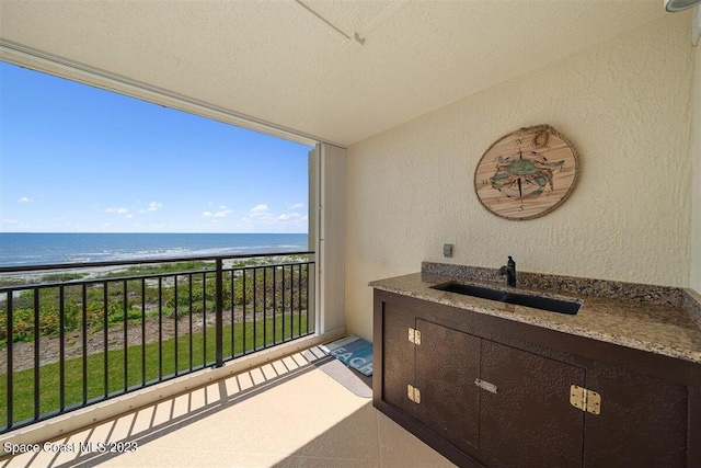 balcony featuring sink and a water view