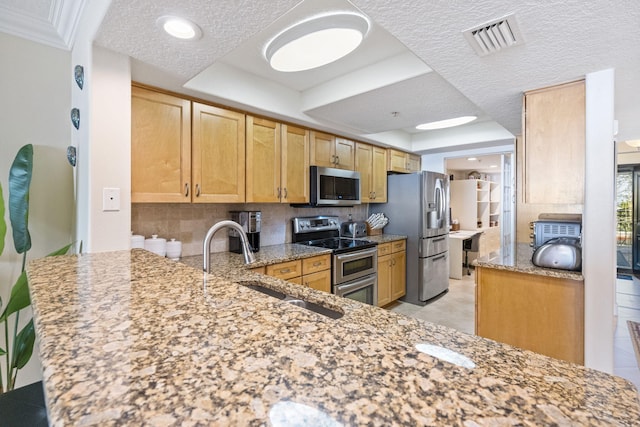 kitchen featuring light stone counters, appliances with stainless steel finishes, light tile floors, backsplash, and kitchen peninsula