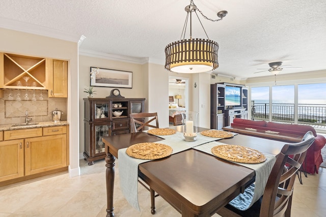 tiled dining area with ornamental molding, sink, ceiling fan, and a textured ceiling