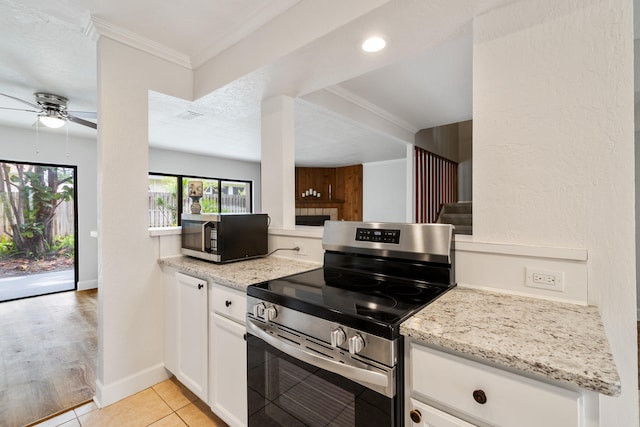 kitchen with appliances with stainless steel finishes, ceiling fan, light tile floors, white cabinetry, and crown molding