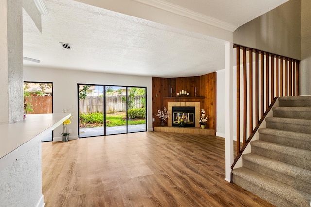 unfurnished living room with a fireplace, light hardwood / wood-style floors, a textured ceiling, and wooden walls