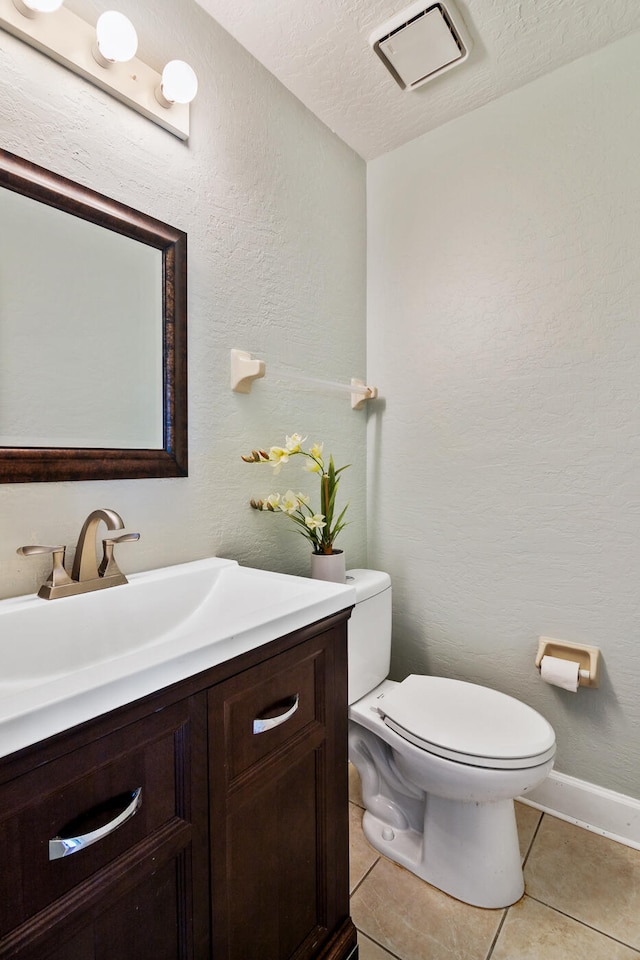 bathroom featuring toilet, tile flooring, vanity, and a textured ceiling