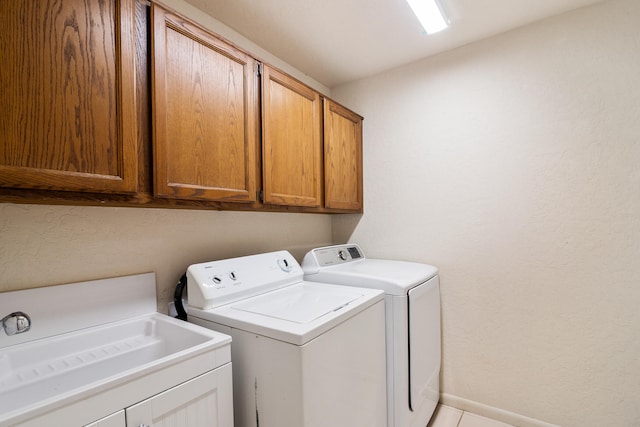 clothes washing area featuring cabinets, sink, and separate washer and dryer