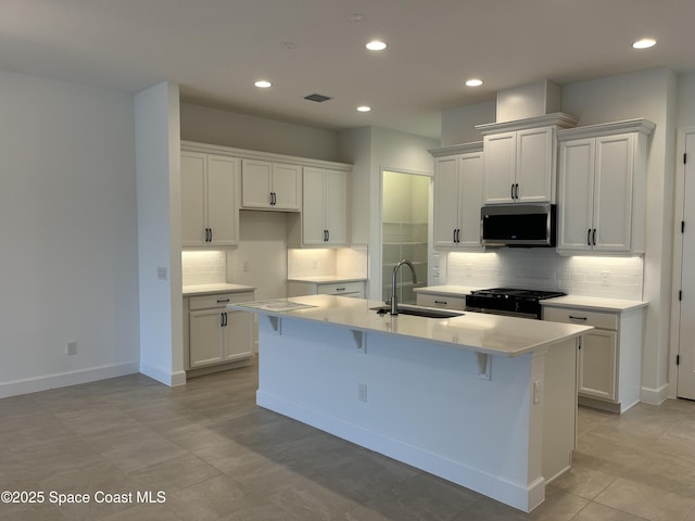 kitchen with white cabinetry, sink, and a center island with sink