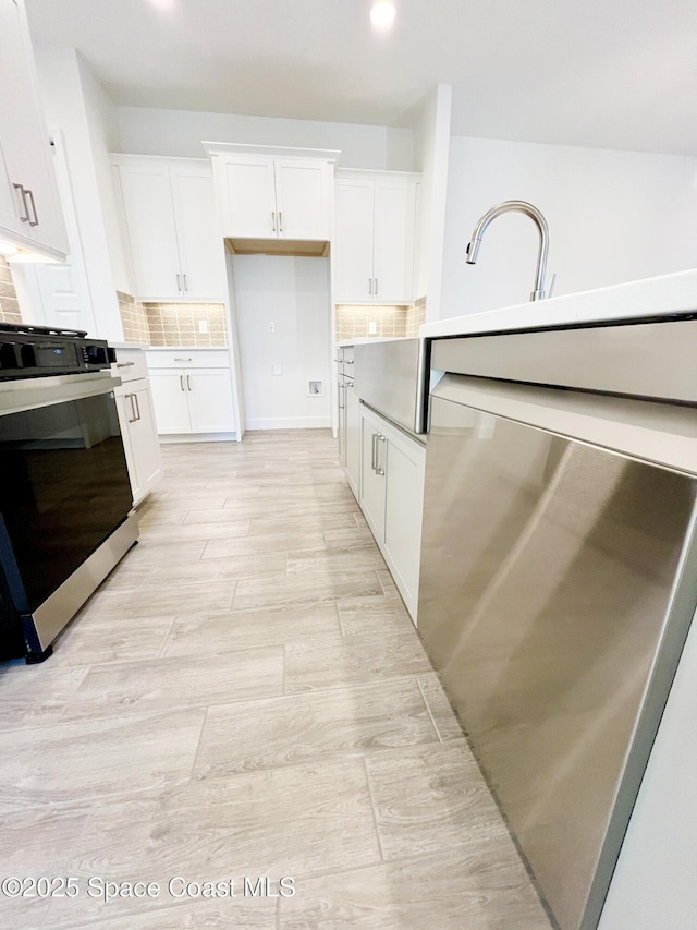 kitchen featuring light countertops, tasteful backsplash, range, and white cabinets