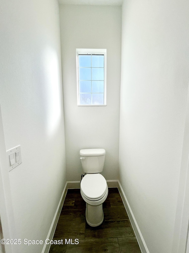 bathroom with toilet, baseboards, and wood finished floors