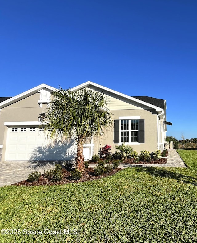 view of front facade featuring a garage, driveway, a front lawn, and stucco siding