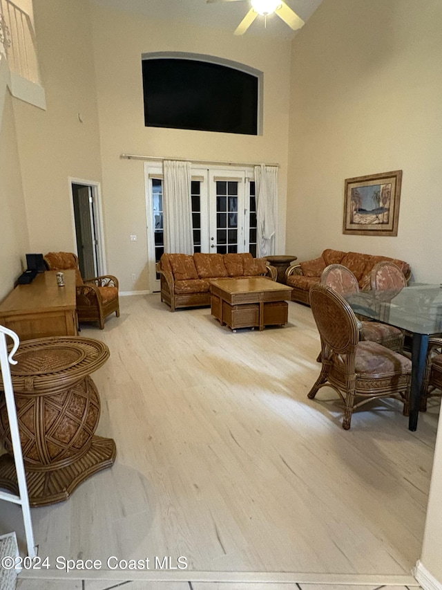 living room with hardwood / wood-style floors, ceiling fan, a high ceiling, and french doors