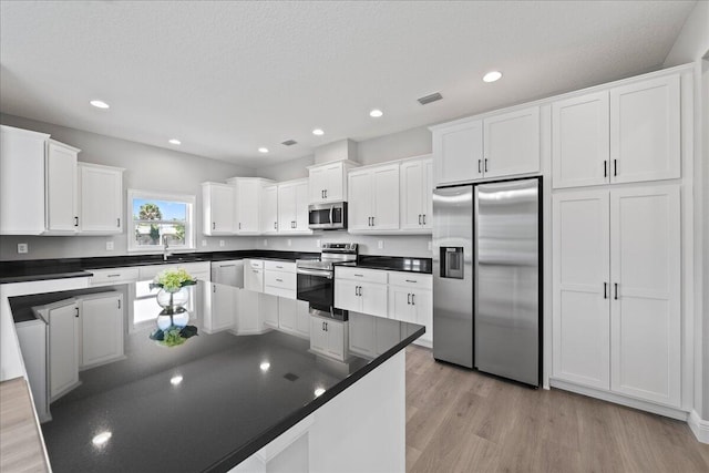 kitchen featuring white cabinetry, stainless steel appliances, a textured ceiling, and light wood-type flooring