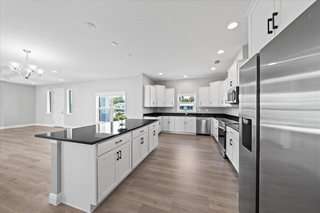 kitchen featuring a healthy amount of sunlight, white cabinetry, stainless steel appliances, and an inviting chandelier