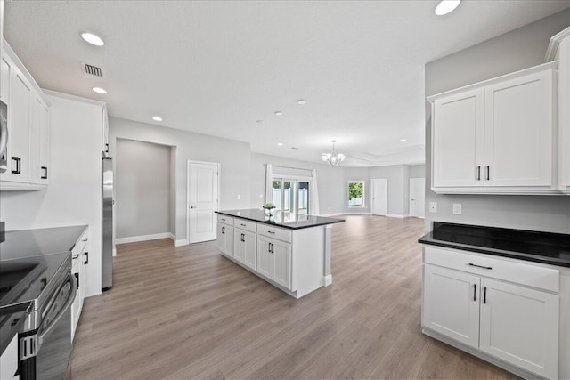 kitchen featuring white cabinetry, light wood-type flooring, a notable chandelier, and appliances with stainless steel finishes