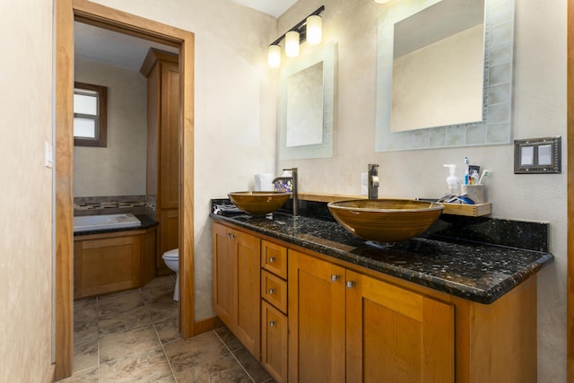 bathroom with vanity, a tub, and toilet