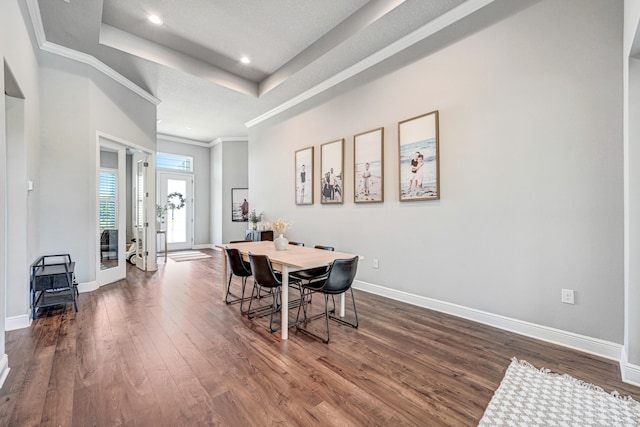 dining room featuring a raised ceiling, crown molding, and dark wood-type flooring