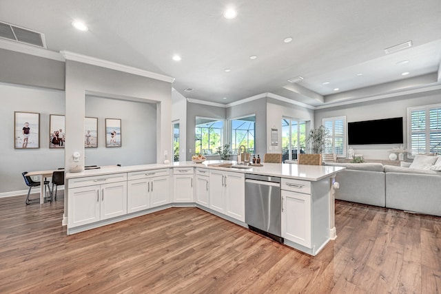 kitchen with kitchen peninsula, dishwasher, a tray ceiling, hardwood / wood-style floors, and white cabinetry