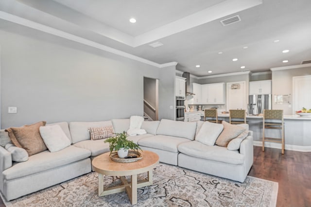 living room featuring a raised ceiling, ornamental molding, and hardwood / wood-style floors