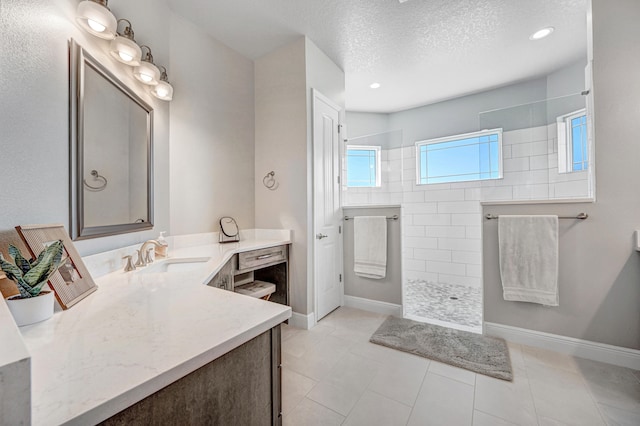 bathroom featuring tile flooring, tiled shower, a textured ceiling, and vanity