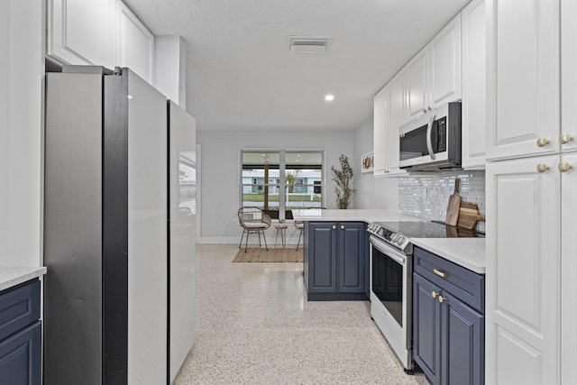 kitchen with kitchen peninsula, decorative backsplash, blue cabinetry, white cabinetry, and stainless steel appliances