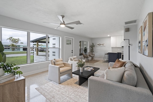 living room featuring ceiling fan and a textured ceiling