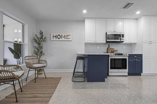 kitchen with white cabinets, blue cabinets, tasteful backsplash, a kitchen bar, and stainless steel appliances