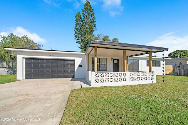 view of front of property featuring covered porch, a garage, and a front yard