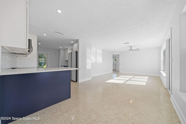 kitchen with stainless steel refrigerator, ceiling fan, tasteful backsplash, kitchen peninsula, and a textured ceiling