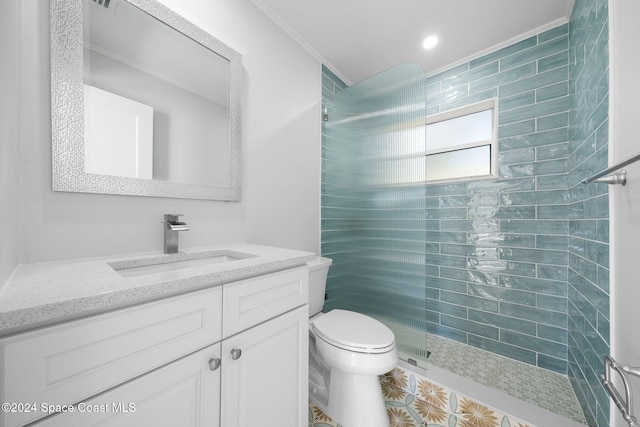 bathroom featuring a tile shower, vanity, toilet, and crown molding