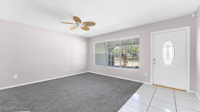 foyer with ceiling fan, a textured ceiling, and light carpet