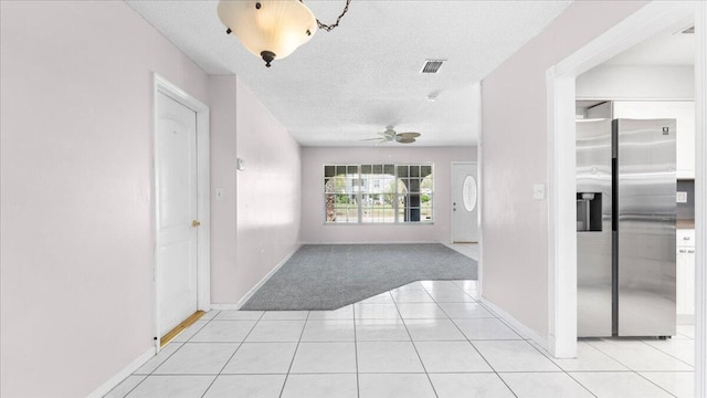 corridor featuring light tile patterned floors and a textured ceiling