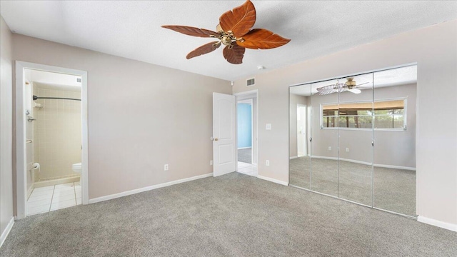 unfurnished bedroom with ceiling fan, light colored carpet, connected bathroom, and a closet