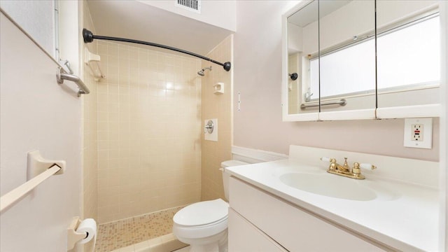 bathroom with a tile shower, vanity, and toilet