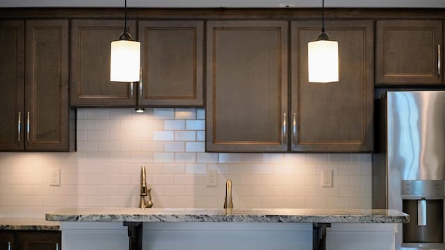 kitchen with backsplash, light stone counters, and stainless steel fridge