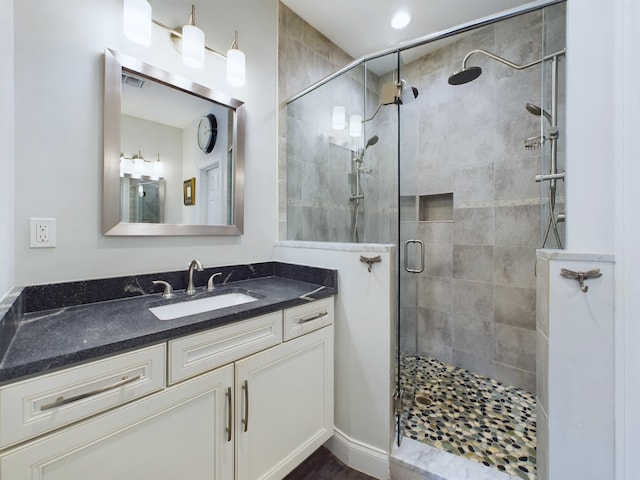 bathroom featuring a shower with shower door and vanity