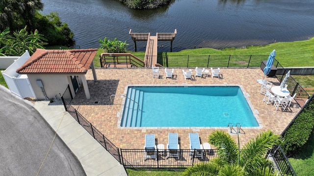 view of pool featuring a water view, a patio area, and a yard