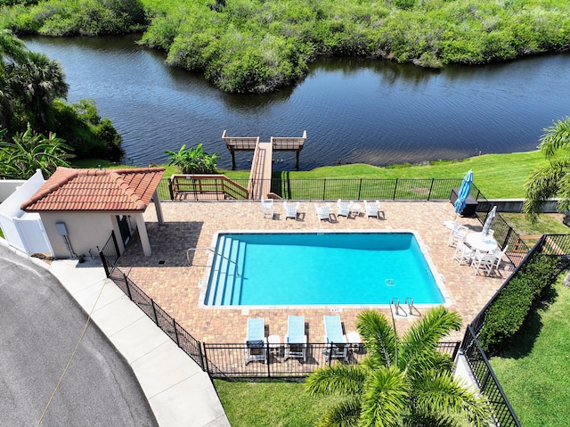 view of pool featuring a patio, a water view, and a lawn