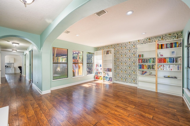 unfurnished room featuring a textured ceiling, dark hardwood / wood-style floors, and built in features