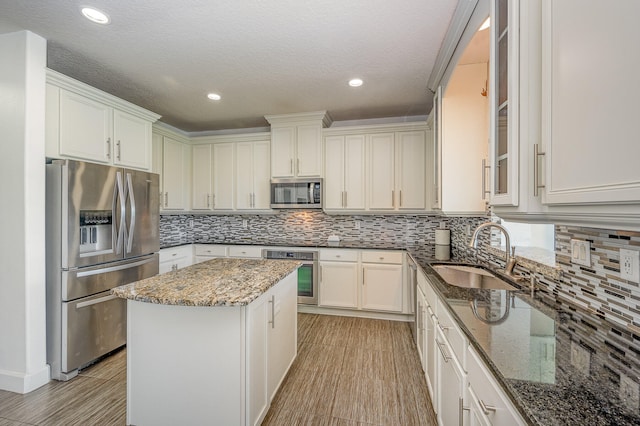 kitchen featuring stainless steel appliances, sink, dark stone counters, and backsplash