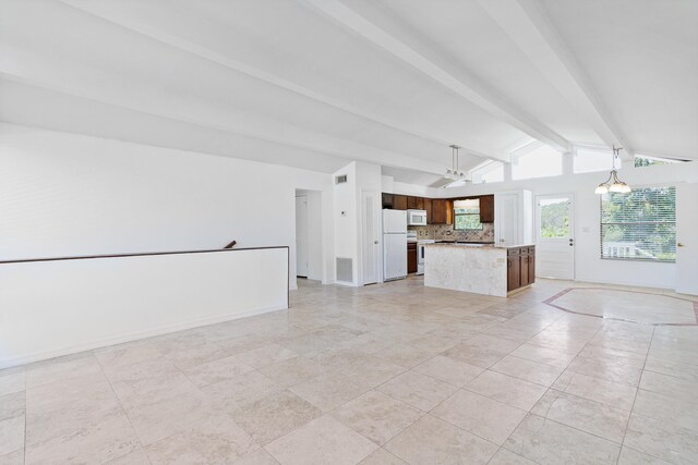 unfurnished living room featuring lofted ceiling with beams and light tile flooring