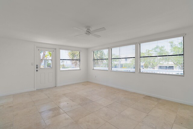 tiled empty room featuring a healthy amount of sunlight and ceiling fan