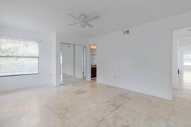 unfurnished bedroom with ensuite bathroom, ceiling fan, and light tile floors