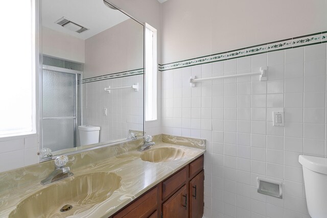 bathroom with tile walls, dual vanity, and toilet