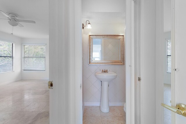 bathroom featuring ceiling fan, tile flooring, and tile walls