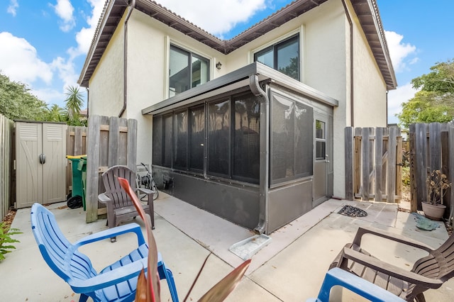 view of property exterior with a patio area and a sunroom