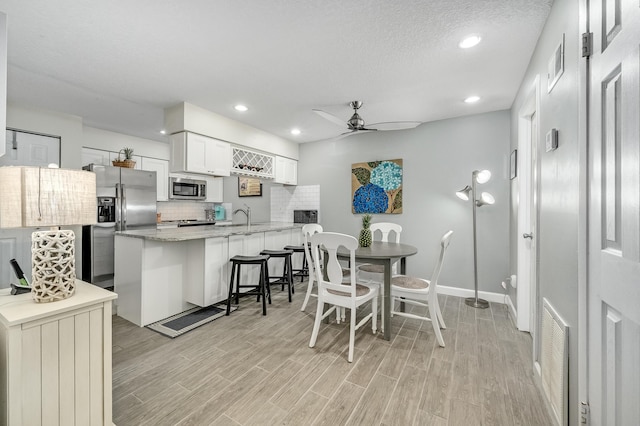 dining area with a textured ceiling, ceiling fan, light wood-type flooring, and sink