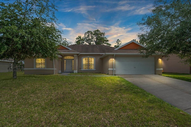 single story home featuring a garage and a lawn