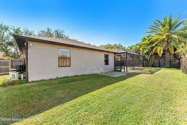 back of house with a yard, a lanai, and a swimming pool