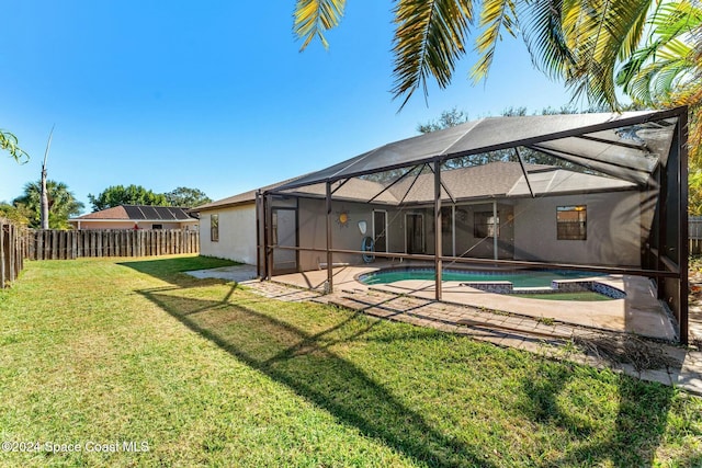 rear view of house with a fenced in pool, glass enclosure, and a lawn