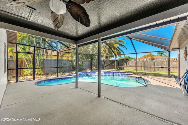 view of swimming pool with glass enclosure, ceiling fan, and a patio area