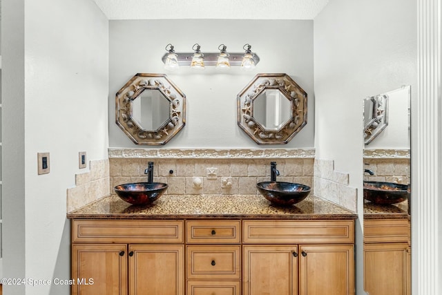 bathroom featuring a textured ceiling, vanity, and backsplash